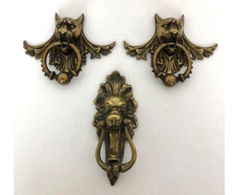 A pair of gilt metal door knockers, in the form of cat's heads, 11 cm, and another door knocker, in the form of a lion's head