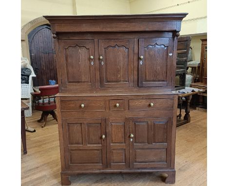 An oak buffet, the top having three cupboard doors, on a base with three drawers and two cupboard doors, 136 cm wideNOTE IVOR