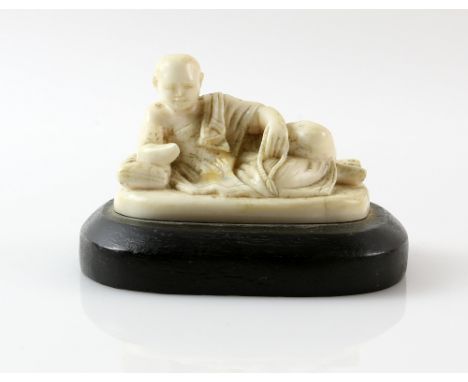 Early 20th century Chinese carved ivory figure of a man reclining, on wooden base, figure 6.5cm wide,PLEASE NOTE: THIS ITEM C