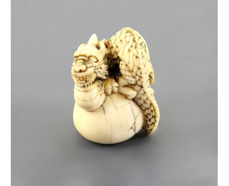 An ivory netsuke of a dragon coiled on a drum (or other object); inscribed with two kanji in a rectangular cartouche on the b