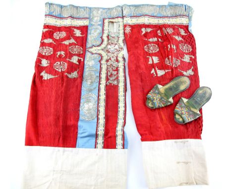 An associated pair of Chinese textile skirts; each one in scarlet and gilt with blue fringes decorated with shou (or other sy