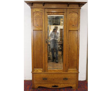 An Arts and Crafts oak wardrobe - probably Liberty & Co, with moulded cornice above door and two parquetry panels, over base 
