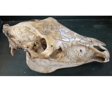 A tribal carved fertility horses skull, decorated with a female figure, animals and hunting scene, 47cm