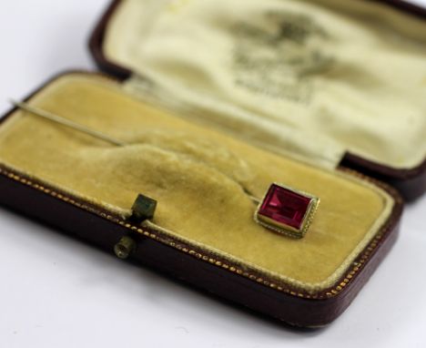 A synthetic sapphire set stick pin, the white metal stick pin, stamped '14k', set with a rectangular cut red stone, weight 1.