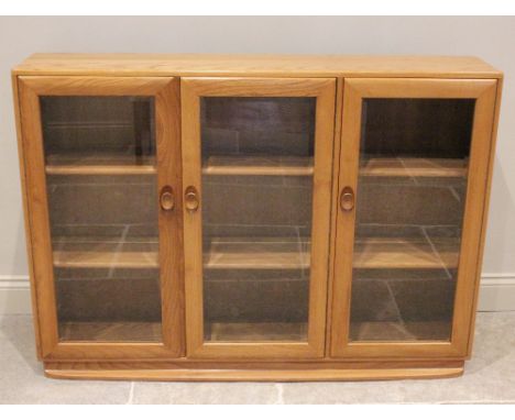 An Ercol light elm floor standing glazed display cabinet, mid 20th century, with one single door and one double door display 