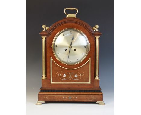 An Edwardian mahogany cased bracket clock, the arched case with a brass swing handle and sphere finials over pillars flanking