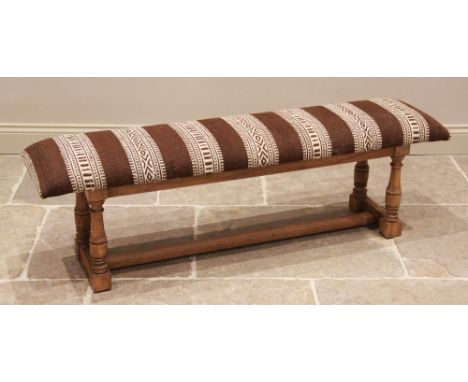 An upholstered hardwood long stool or window seat, late 20th/early 21st century, the rectangular padded seat covered in ethni