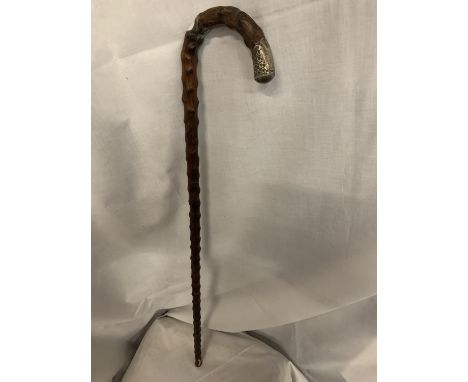 A TEXTURED WOODEN CANE WITH METAL DEISGN TO THE END OF THE HANDLE. SMALL AMOUNT OF DAMAGE TO THE BOTTOM OF THE STICK 