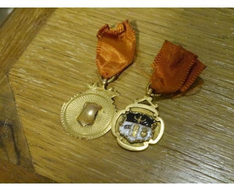 Two 9ct gold fobs or medals, one centred by an enamel crest and bearing the date 1938 to the reverse. (2)