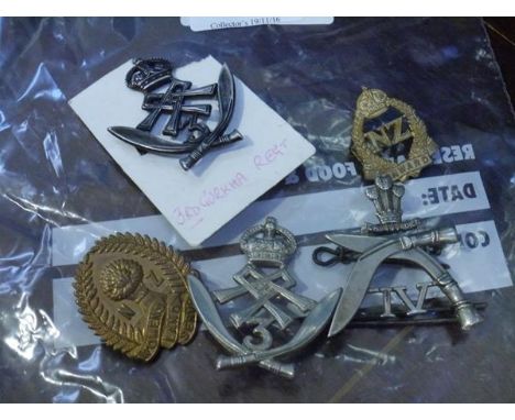 A bag of five military and other badges including Gurkhas and Womens Land Army