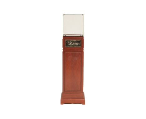 A VINTAGE CHOPARD DISPLAY STAND With glazed display box on wood pedestal, the front with Chopard logo, fitted for electricity