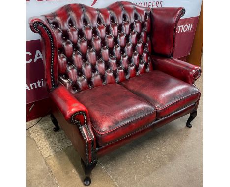 An oxblood red leather Chesterfield wingback settee 