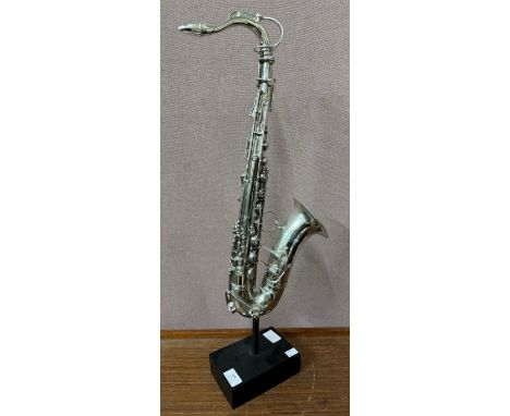 A silvered sculpture of a saxophone on stand 