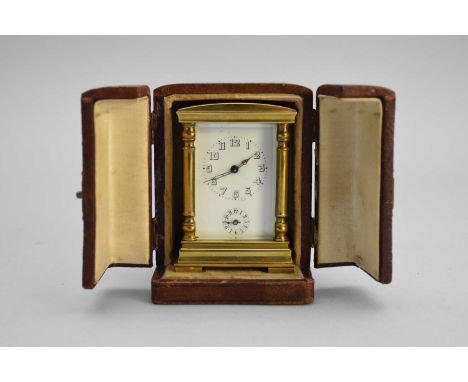 A French gilt brass miniature carriage alarm clock, the four-glass case with corner columns, the white enamel dial with black