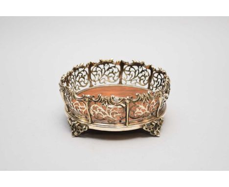 A 19th century silver plated bottle coaster, with decorative scroll pierced border and raised on four bracket feet, 18cm diam