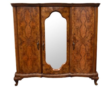 A 19th century French walnut serpentine armoire, the ogee cornice carved with acanthus leaves above three doors, the centre d