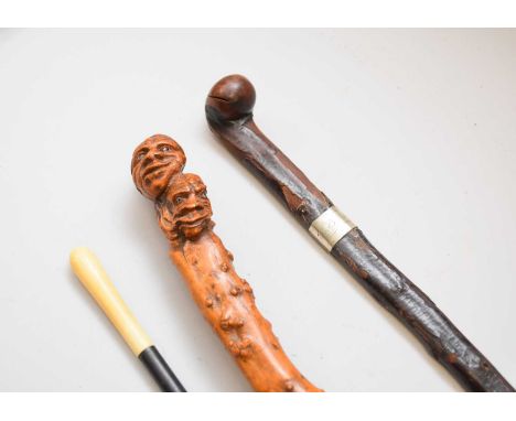 A carved wood walking stick, possibly yew, the pommel carved as two grotesque faces, the staff left natural and of knotty app