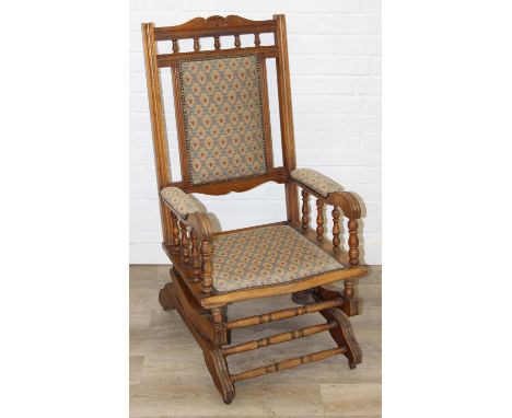 An early 20th century rocking chair with decorative floral upholstery, possibly American, 107cm tall
