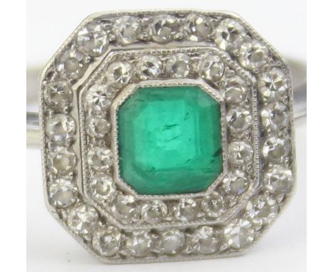 [4.39g, L] - an Art Deco period platinum ring set with a cluster of diamonds and emerald, the central emerald cut green emera