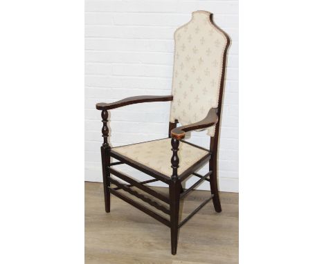An Arts &amp; Crafts period high back armchair in the manner of Liberty &amp; Co, turned supports with shaped arms, cream fle