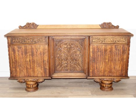 A large 17th century style heavily carved oak sideboard with a central carved cupboard flanked by 2 plain cupboards under 2 c