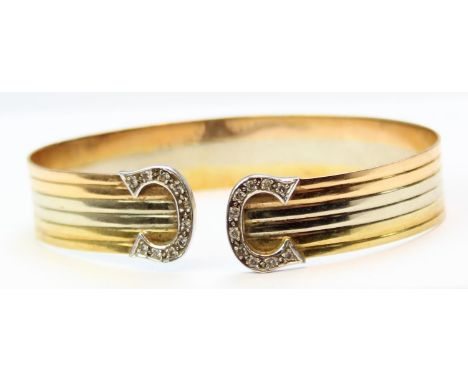 [17.15g] - in the manner of Cartier - an 18ct yellow and white gold torque or cuff bracelet set with diamond encrusted revers