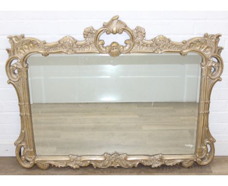A large vintage Rococo style gilt framed over mantel mirror with decorative floral scrolled border, distressed, 110cm x 87cm