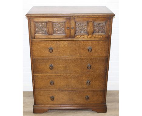 An unusual four drawer oak chest of drawers or tall boy with panels and two door cupboard to top, likely by Crown AY furnitur