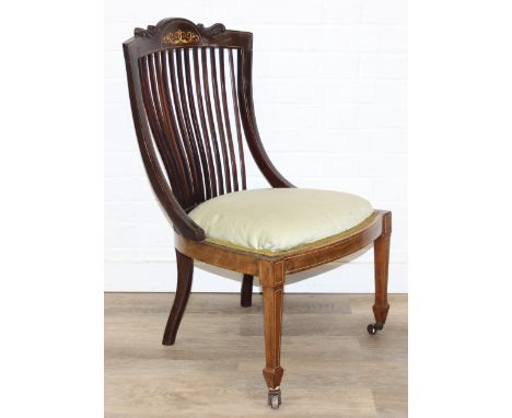 An antique mahogany low chair in the manner of James Shoolbred, with slatted back and decorative inlay, spade legs with brass