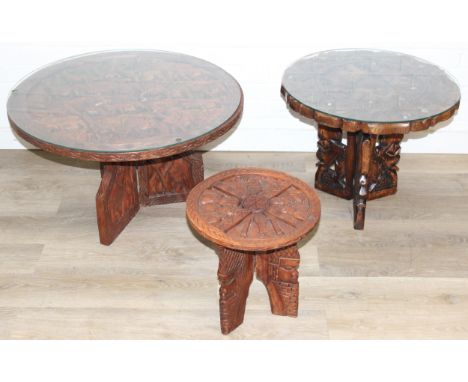 Three African carved hardwood folding tables, the tops carved with elephants, rhinos, giraffes etc, the largest 75cm diam x 4