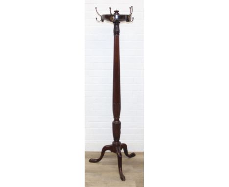 An antique mahogany coat stand with reeded pillar and carved with wheat sheaths, five brass hooks and tripod base with pad fe