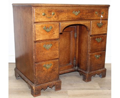 A Georgian oak kneehole desk, one long drawer over six short drawers with cupboard, brass fittings and bracket feet, 18th cen