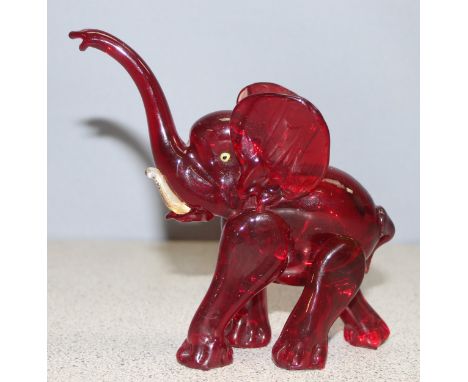 Attributed to Vetreira Artistica Barovier or Martinuzzi, a small red glass model of an elephant walking, trunk raised, inset 