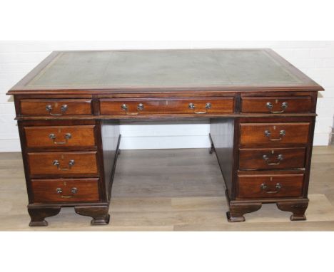 A vintage mahogany partner's three-part pedestal desk with inset green leather top, eighteen drawers [nine on either side], 2