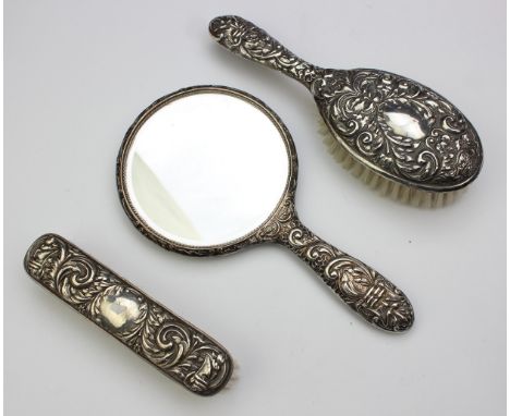Two silver backed brushes and a silver hand mirror, profuse embossed decoration, marked for Birmingham 1979 by Broadway &amp;