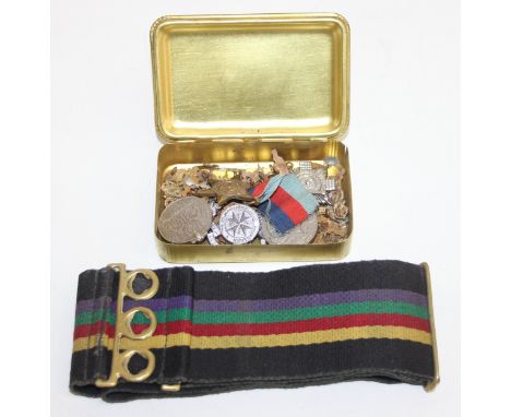 A WW1 Princess Mary tin containing a large qty of assorted military related badges and medals, a military belt etc