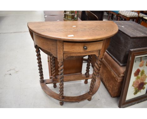 A traditional oak demi lune hall table, having twist gate leg and back flap, width approx. 77cm