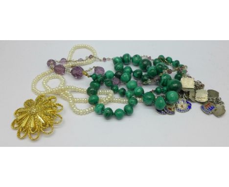 A silver charm bracelet lacking fastener, a malachite necklace, two other necklaces and a brooch