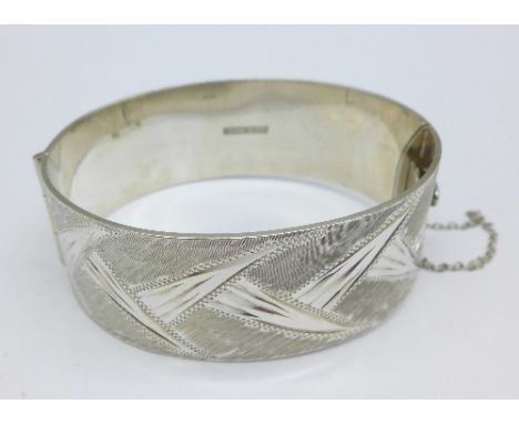 A silver machine cut bangle with safety chain, Birmingham 1966-67, 53.5g