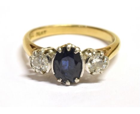 A DIAMOND AND SAPPHIRE THREE STONE RING The ring set with a faceted oval blue sapphire measuring 6mm X 5mm and flanked each s