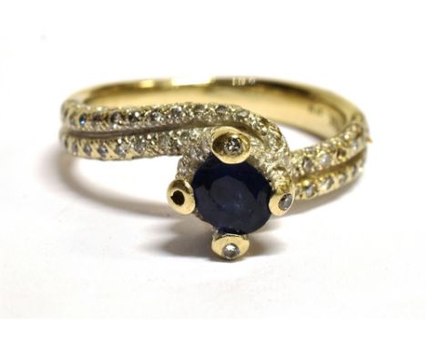 A STAMPED 18K SAPPHIRE AND DIAMOND CROSS OVER RING The ring in white metal and centrally set with a faceted oval sapphire of 