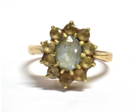 MARKED 9CT VINTAGE FLOWER HEAD RING The flower head comprising of an oval pale blue gem surrounded by light yellow/white, qua