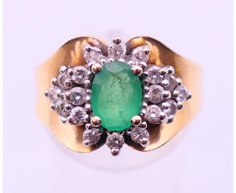 A 14 ct gold, emerald and diamond cluster ring, the oval emerald (7.1 x 5.1mm), surrounded by eighteen brilliant cut diamonds