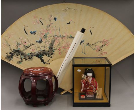 A cased Japanese doll, a Chinese scroll, a small wooden barrel seat and a large fan-shaped wall hanging. The seat 29 cm high.