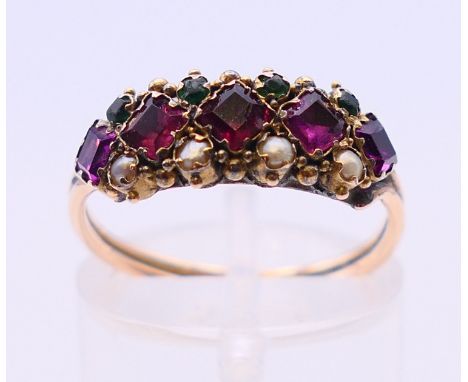 An unmarked yellow metal amethyst, emerald and seed pearl ring, circa 1900.  Ring size N.