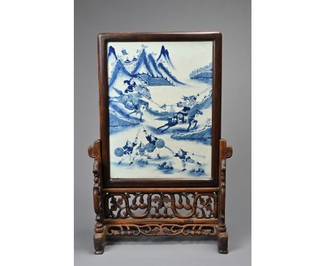 A CHINESE HARDWOOD TABLE SCREEN WITH PORCELAIN TILE, 20TH CENTURY. The porcelain tile decorated in underglaze blue with figur