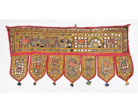 A VINTAGE INDIAN EMBROIDERED MIRROR WORK WALL HANGING. Of rectangular form suspending seven tasselled pelmets, decorated with