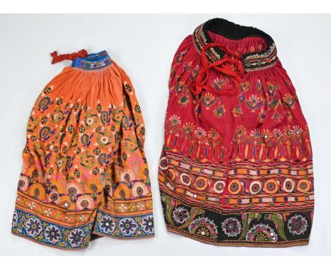 TWO VINTAGE INDIAN EMBROIDERED COTTON AND MIRROR WORK SKIRTS. The first orange ground, embroidered with peacocks, flowerheads