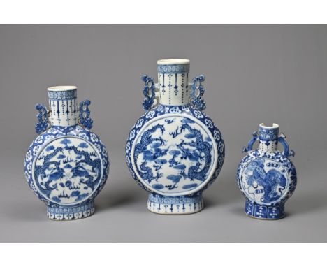 THREE CHINESE BLUE AND WHITE PORCELAIN MOON FLASKS, 19TH CENTURY. Of graduating sizes decorated with dragons and guardian dog