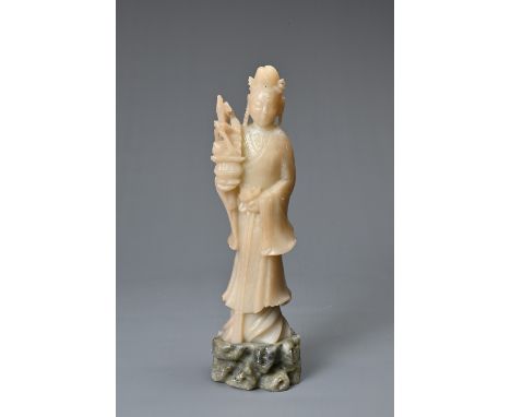 A VINTAGE CHINESE CARVED SOAPSTONE FIGURE OF GAUNYIN, 20TH CENTURY. Standing on rock form base holding a basket with peach an